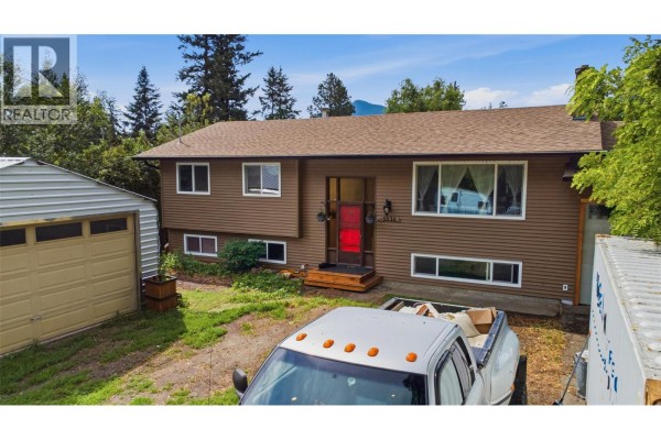 Aerial front view of a brown house with a red door, surrounded by trees and a driveway. - 5830 6 Highway, Lavington