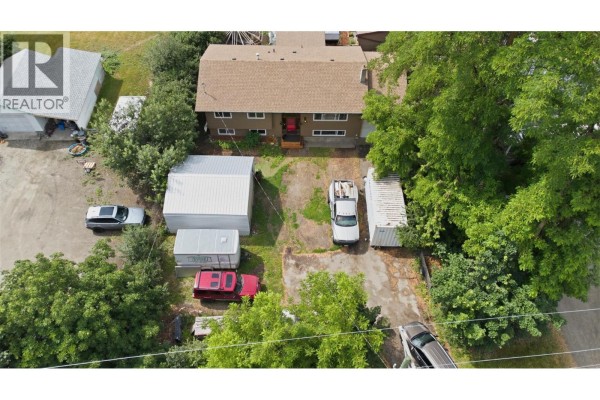 Aerial view of the property with multiple buildings, vehicles, and surrounding trees. - 5830 6 Highway, Lavington