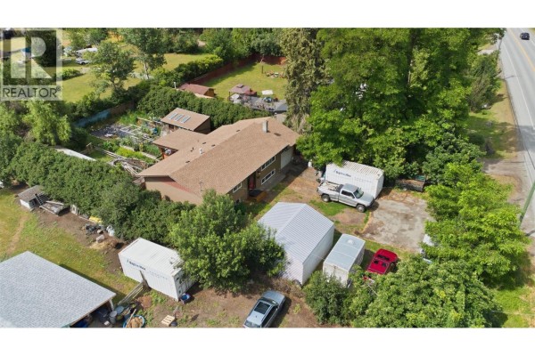 High aerial view of the property showing the house, outbuildings, yard, and distant road. - 5830 6 Highway, Lavington