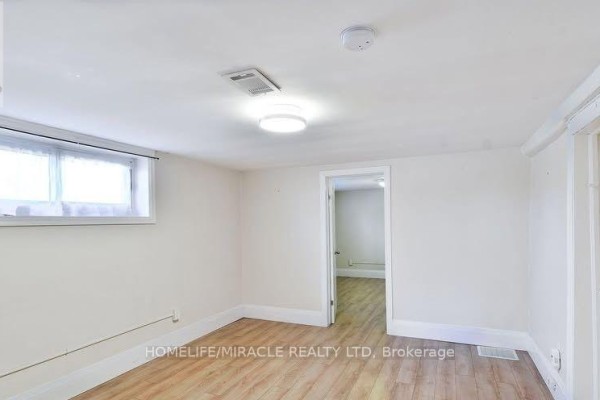 Room with light wood flooring, white walls, a window, and an open doorway. - 584 Montgomery Street, Oshawa