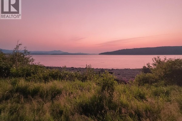 Ocean view at sunset with calm water and distant mountains under a pink sky. - 585 1st St, Sointula