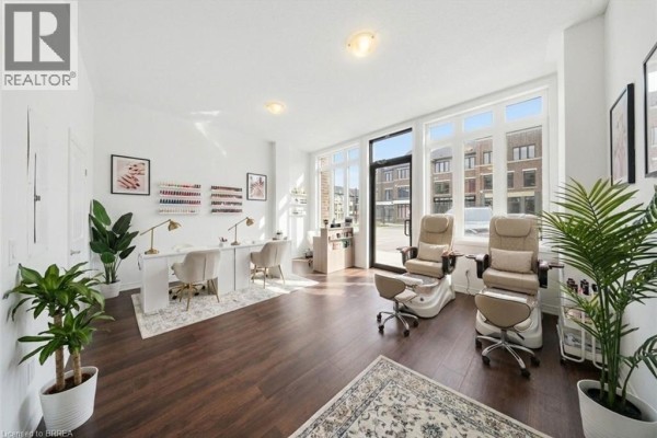 Wooden deck with black metal railing and views of townhouses and a field. - 585 Colborne Street E Unit# 107, Brantford
