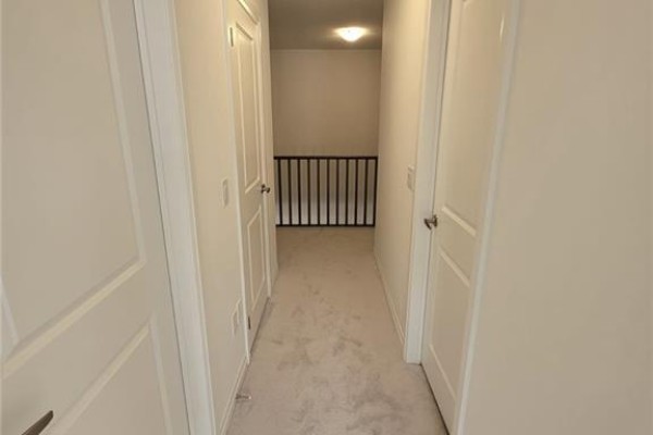 Hallway with multiple doors and access to a staircase landing with black railing. - 585 Colborne Street E Unit# 913, Brantford