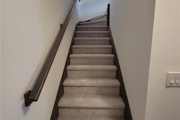Carpeted staircase with dark wood trim and a wooden handrail. - 585 Colborne Street E Unit# 913, Brantford