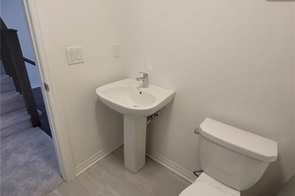Powder room with white pedestal sink, toilet, and light grey tiled floor. - 585 Colborne Street E Unit# 913, Brantford
