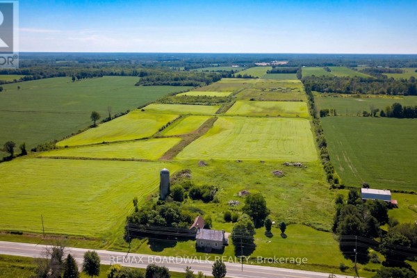 Aerial view of a rural landscape with patchwork green fields, a silo, and farm buildings. - 585 Fallbrook Road, Tay Valley