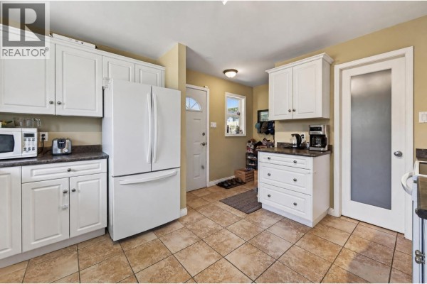 White kitchen with a refrigerator, microwave, white cabinetry, and tiled flooring. - 5855 Dallas Drive, Kamloops