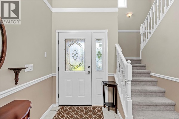 Interior entryway with a white door, beige walls, white trim, and a carpeted staircase. - 5857 Quarry Cres, Nanaimo