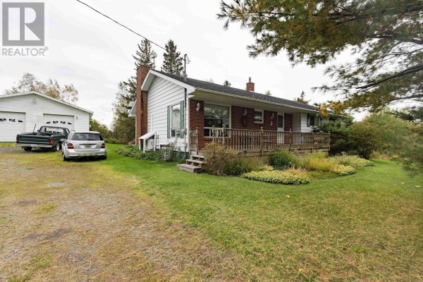 A white brick bungalow with a double garage and parked vehicles. - 5862 Highway 6, Linden