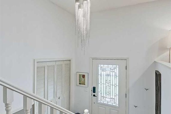 Interior foyer with white walls, bi-fold doors, and a staircase. - 5864 Dalford Hill Nw, Calgary