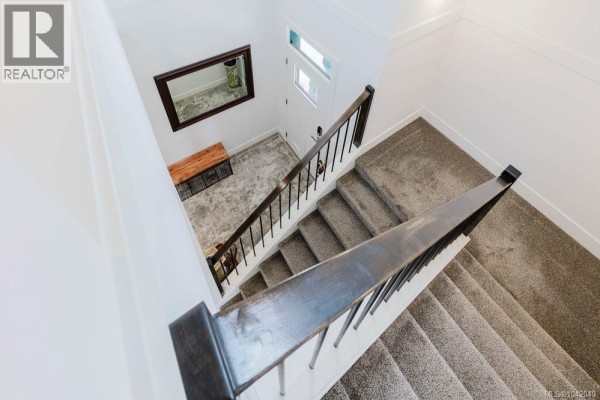 Bright kitchen with sliding door to backyard, featuring a gas stove and white backsplash - 5869 Deuchars Dr, Duncan