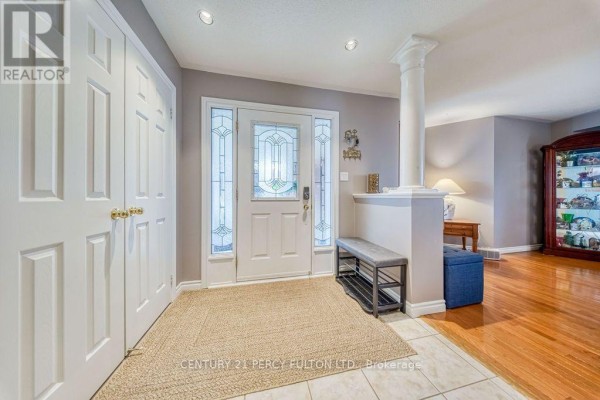 Interior entryway with white double doors, a beige rug, a white bench, and a glass-paneled front door. - 589 Blackwood Boulevard, Oshawa