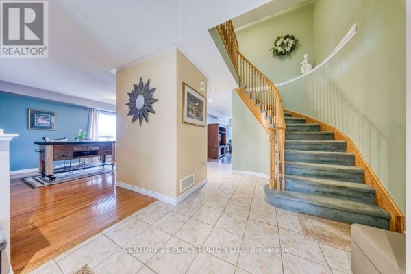 Interior foyer with a curved staircase, cream-colored tile flooring, and light green walls. - 589 Blackwood Boulevard, Oshawa