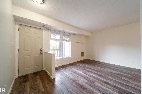 Entrance area of a townhouse unit with a white door and large window. - 5898 172 St Nw, Edmonton