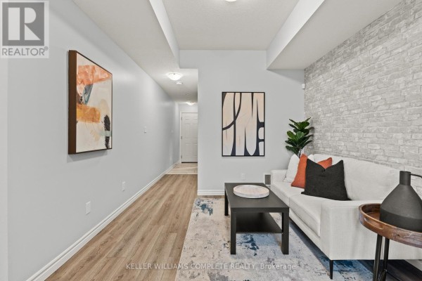 Living room with white sofa, black coffee table, and accent wall with modern art. - 59 - 107 Westra Drive, Guelph