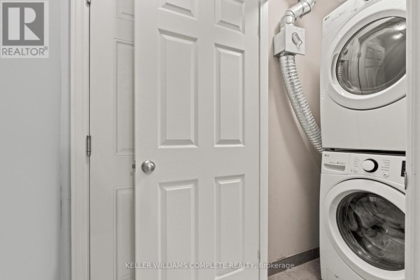 Laundry area with stacked white washer and dryer, and adjacent white doors. - 59 - 107 Westra Drive, Guelph
