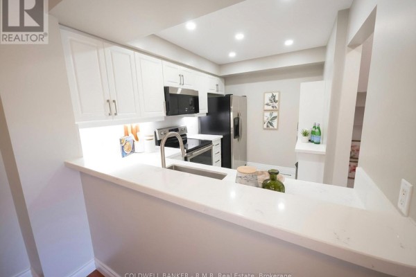 Kitchen with white cabinets, stainless steel appliances, and a quartz countertop breakfast bar. - 59 - 2 Hedge End Road, Toronto