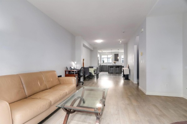 Living room with a tan leather sofa, glass coffee table, and dining area in background. - 59 8355 164 Street, Surrey