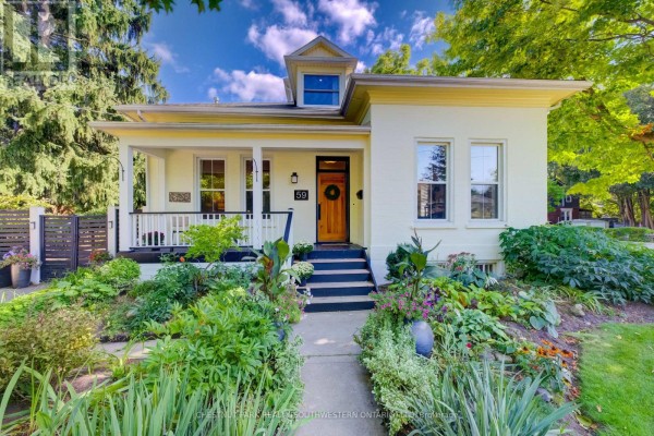 Close-up of the front porch with white railings, a wooden door, and two potted mums. - 59 Allen Street W, Waterloo