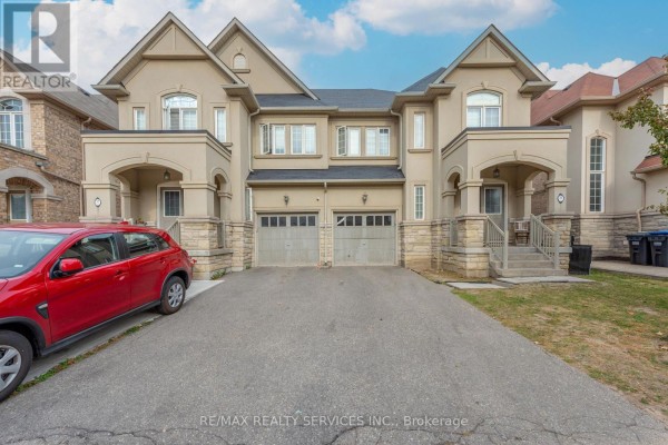 Front view of a beige townhouse complex with two garage doors and driveways. - 59 Beachville Circle, Brampton