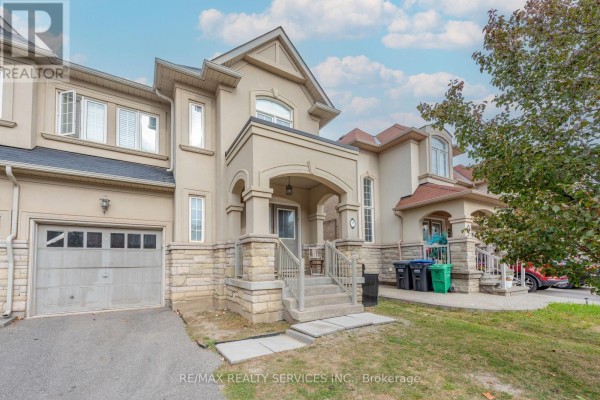 View of the beige townhouse exterior with a garage, entrance, and grassy area. - 59 Beachville Circle, Brampton