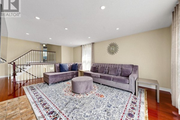Purple tufted sofas, ottoman, ornate rug, and staircase - 59 Brennan Road Ajax