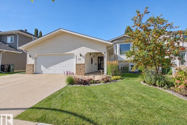 Front exterior of a white house with a large driveway, lawn, and decorative landscaping. - 59 Cimmaron Wy, Sherwood Park