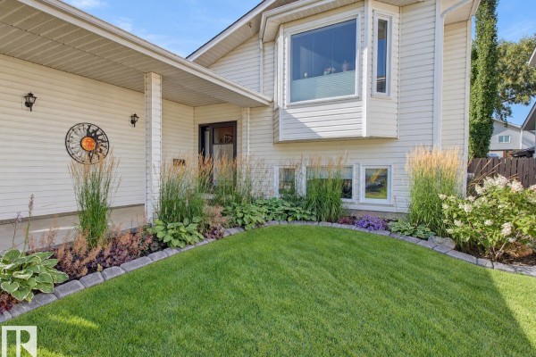 View of the house entrance, bay window, and manicured lawn with mature shrubs and flowers. - 59 Cimmaron Wy, Sherwood Park