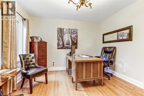 Home office with a wood desk, leather chair, filing cabinet, and wall art. - 59 Decou Road, Simcoe