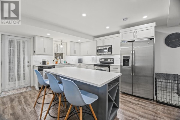 Wooden deck area with a covered grill, white door, and wood siding. - 59 Freshwater Road, St  John S