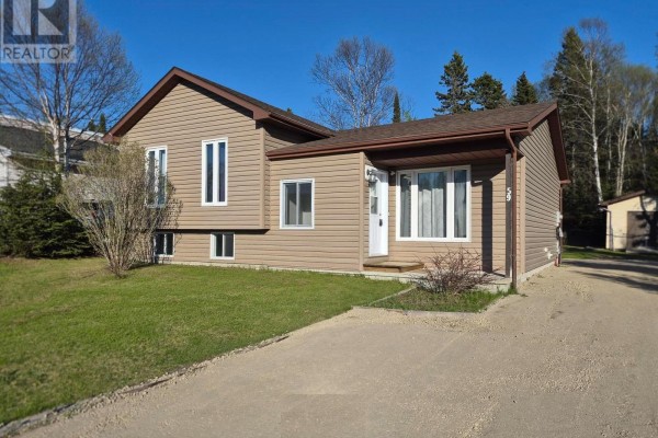 Front of the house with a driveway leading to the entrance, surrounded by green lawn and trees. - 59 Hemlo Drive, Marathon