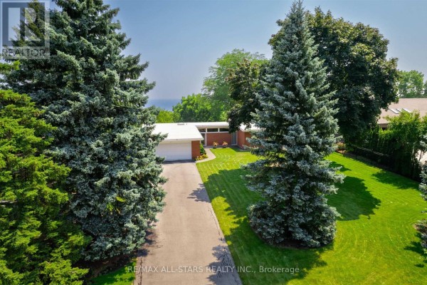 Wide aerial shot showcasing the property's extensive green lawn and mature trees surrounding a brick home. - 59 Hill Crescent, Toronto