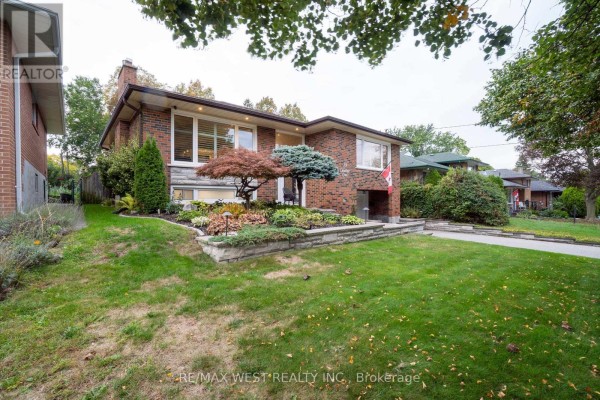 Side view of the brick bungalow showing mature trees and well-kept front yard. - 59 Landfair Crescent, Toronto