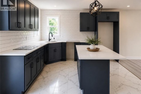 L-shaped kitchen with dark grey cabinets, white subway tile backsplash, and a large island. - 59 Malibu Street, Marysville