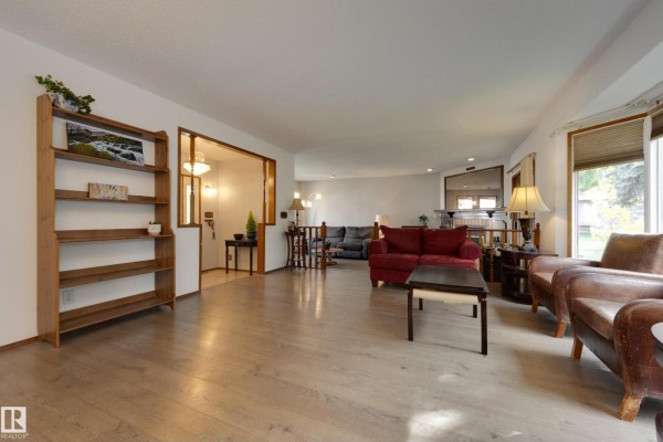 Living area with light wood flooring, a red sofa, and armchairs. - 59 Spruce Av, Sherwood Park