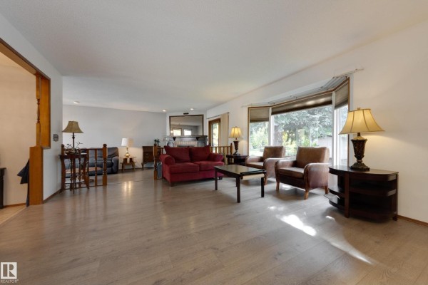 Spacious living room with bay window, sofa, armchairs, and wood flooring. - 59 Spruce Av, Sherwood Park