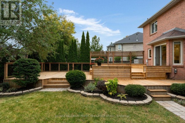 Multi-level wooden deck in a backyard with manicured landscaping and a brick house. - 590 Gagnon Place, Newmarket