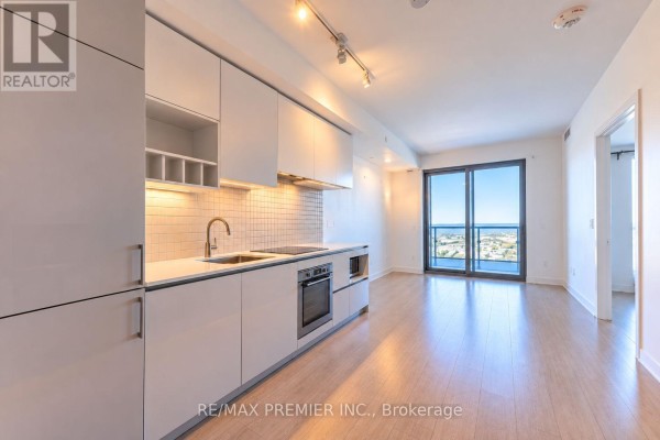 Open concept living area and kitchen with large windows and light wood floors. - 5901 - 950 Portage Parkway, Vaughan