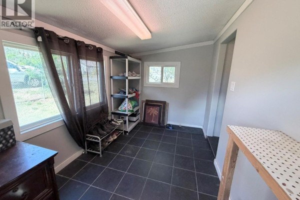Another angle of mobile home with mountains in the background and grassy yard. - 591 Davidson Crescent, Lillooet