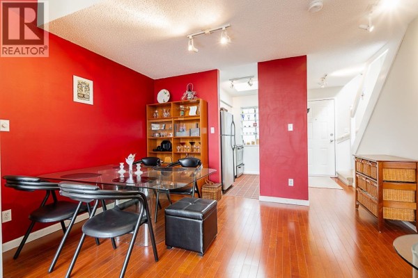 View from dining area to kitchen and hallway, with glass table and red wall. - 592 W 16th Avenue, Vancouver
