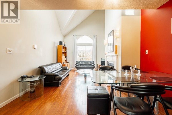 Spacious living and dining area with vaulted ceiling, fireplace, wood floors, and large arched window. - 592 W 16th Avenue, Vancouver
