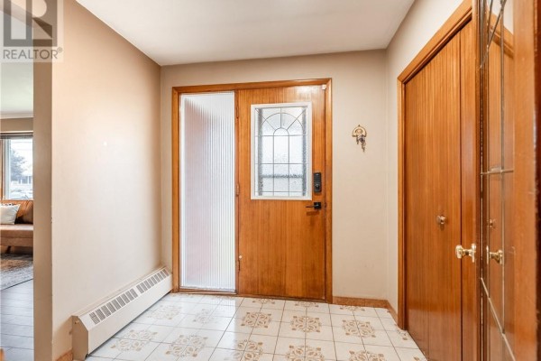Interior entryway with wood double doors, tiled floor, and white baseboard heating. - 593 Danforth Avenue, Sudbury