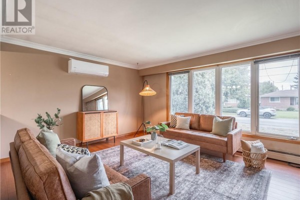 Living room with two brown leather sofas, a white coffee table, and large windows. - 593 Danforth Avenue, Sudbury