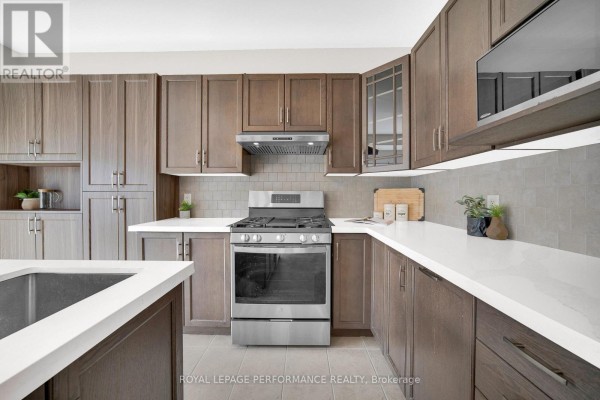 Kitchen with dark wood cabinets, quartz counters, and stainless steel appliances - 593 Pinawa Circle Ottawa