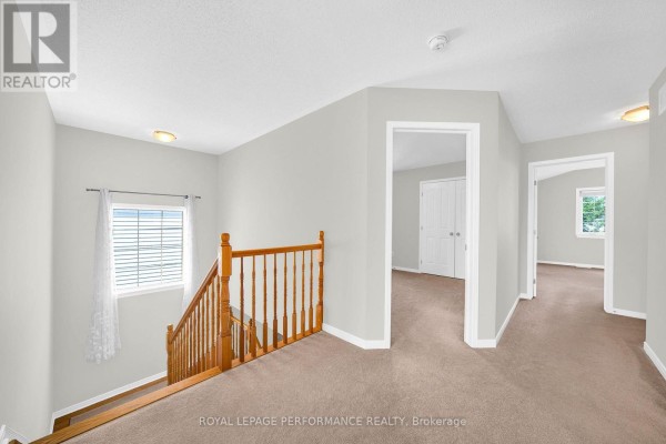 Hallway with wooden banister staircase and doorways to rooms - 593 Pinawa Circle Ottawa