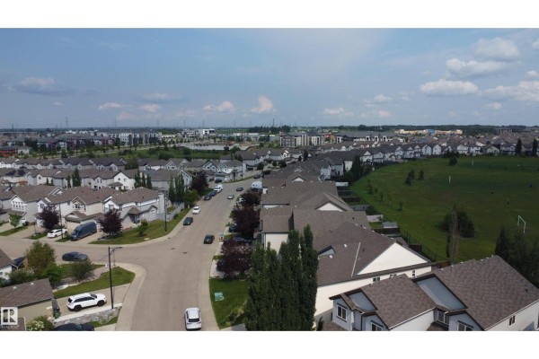 Aerial view of a suburban street with houses, cars, and a grassy field. - 5931 12 Av Sw, Edmonton