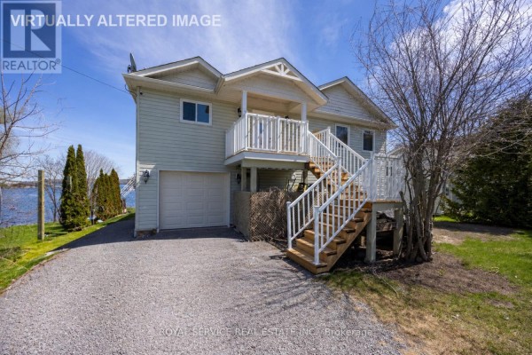 A light blue siding house with a garage and white stairs leading to the deck. - 595 Foley Road, Otonabee South Monaghan