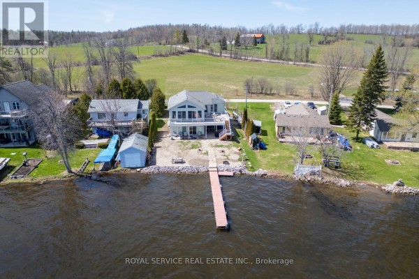 Aerial view of houses on a lakefront with a dock extending into the water. - 595 Foley Road, Otonabee South Monaghan