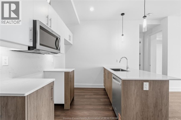 View of a contemporary kitchen with white upper cabinets and two-toned island cabinets. - 595 Lily Mac Unit# 205, Windsor