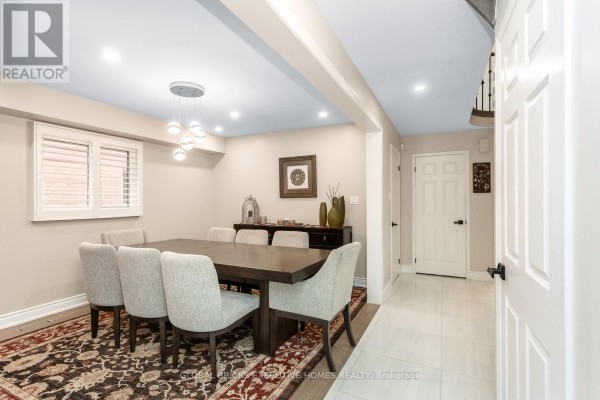 Dining room with dark wood table, upholstered chairs, ornate rug, and modern pendant light - 5952 Grossbeak Drive Mississauga